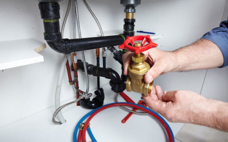 Hands Of Professional Plumber With Valve — Plumbers in Exeter, NSW