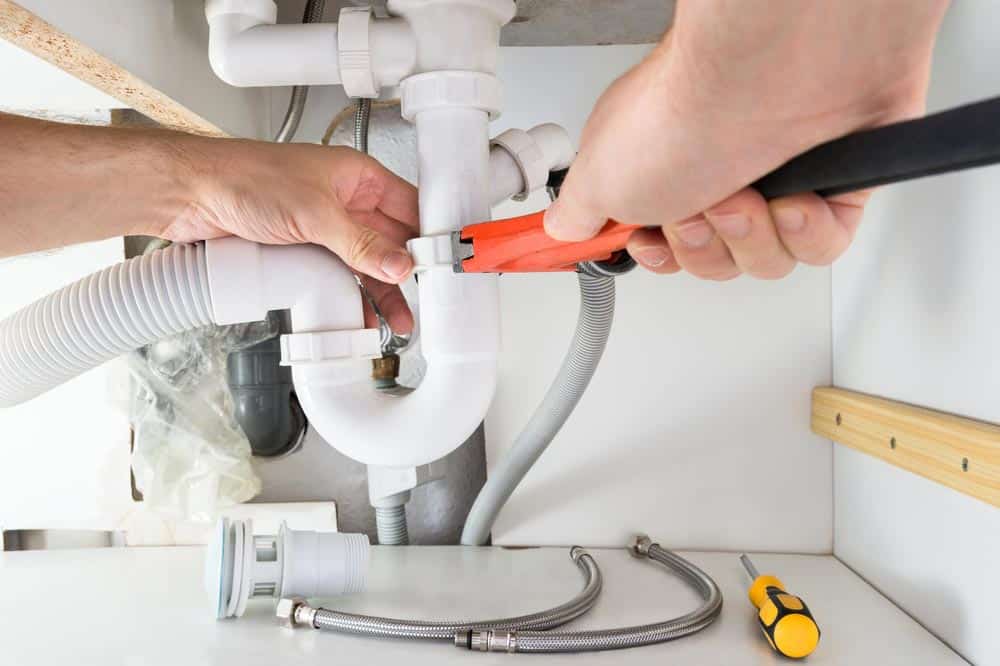 Male Plumber Fixing Sink — Plumbers in Bowral, NSW
